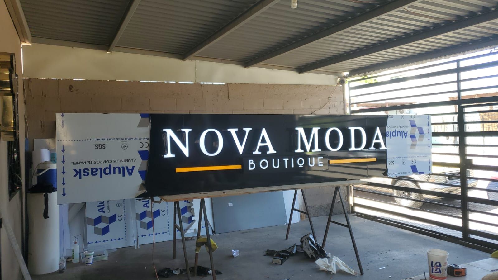 El anuncio de Nova Moda Boutique sobre burros de trabajo, rodeado de láminas de aluminio compuesto sin desforrar.