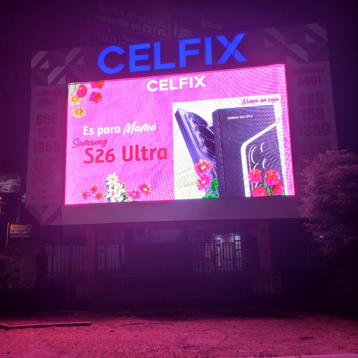 Unipolar de Celfix de noche: pantalla LED a todo color bajo letras de canal azules montadas en marco de panel facetado.