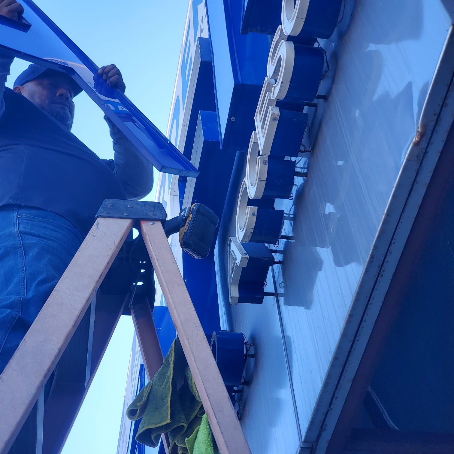 El técnico desmonta una letra desde la escalera para limpiarla con las microfibras.