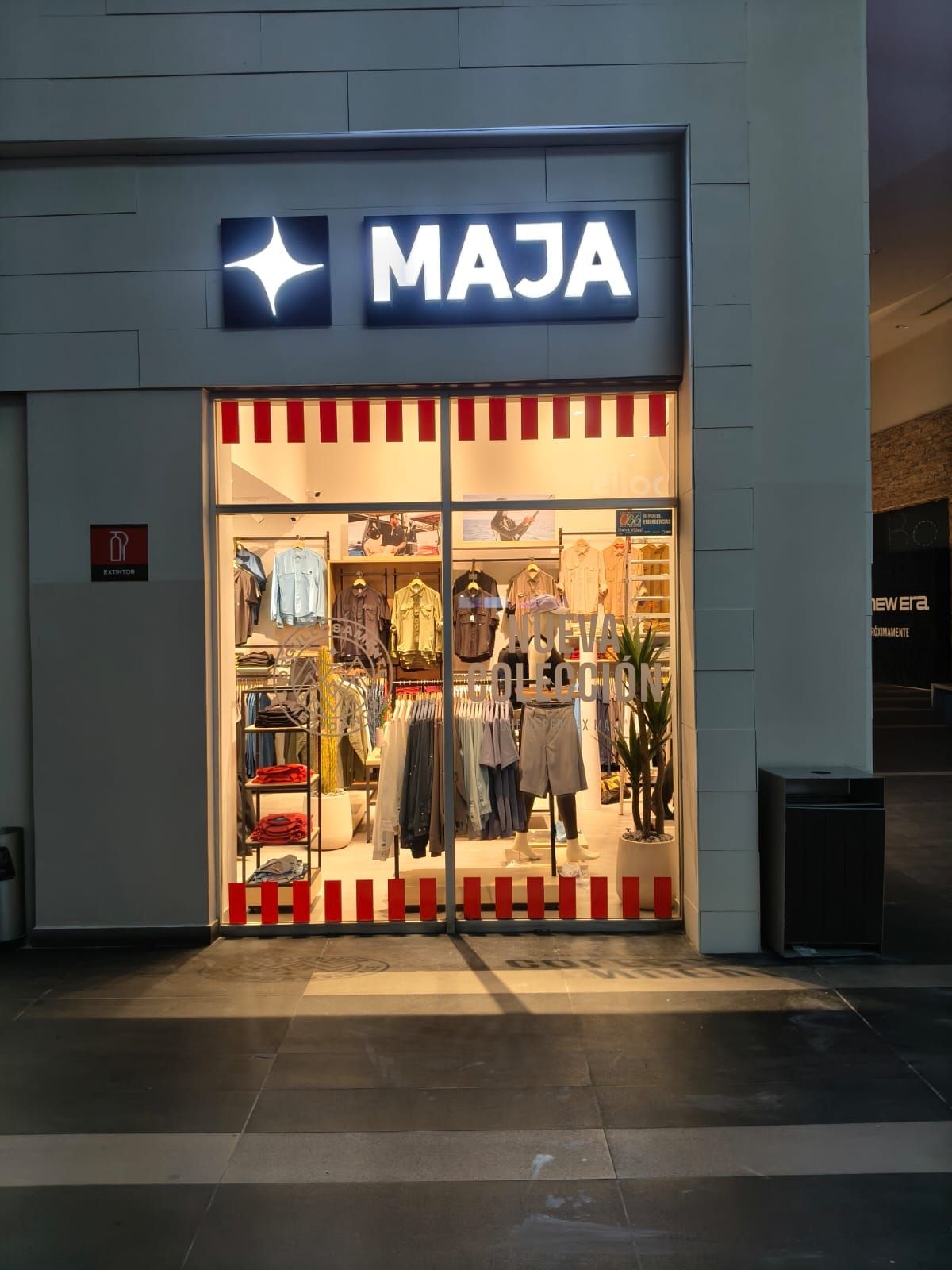 Charola luminosa de MAJA encendida sobre el acceso de la tienda en plaza comercial.